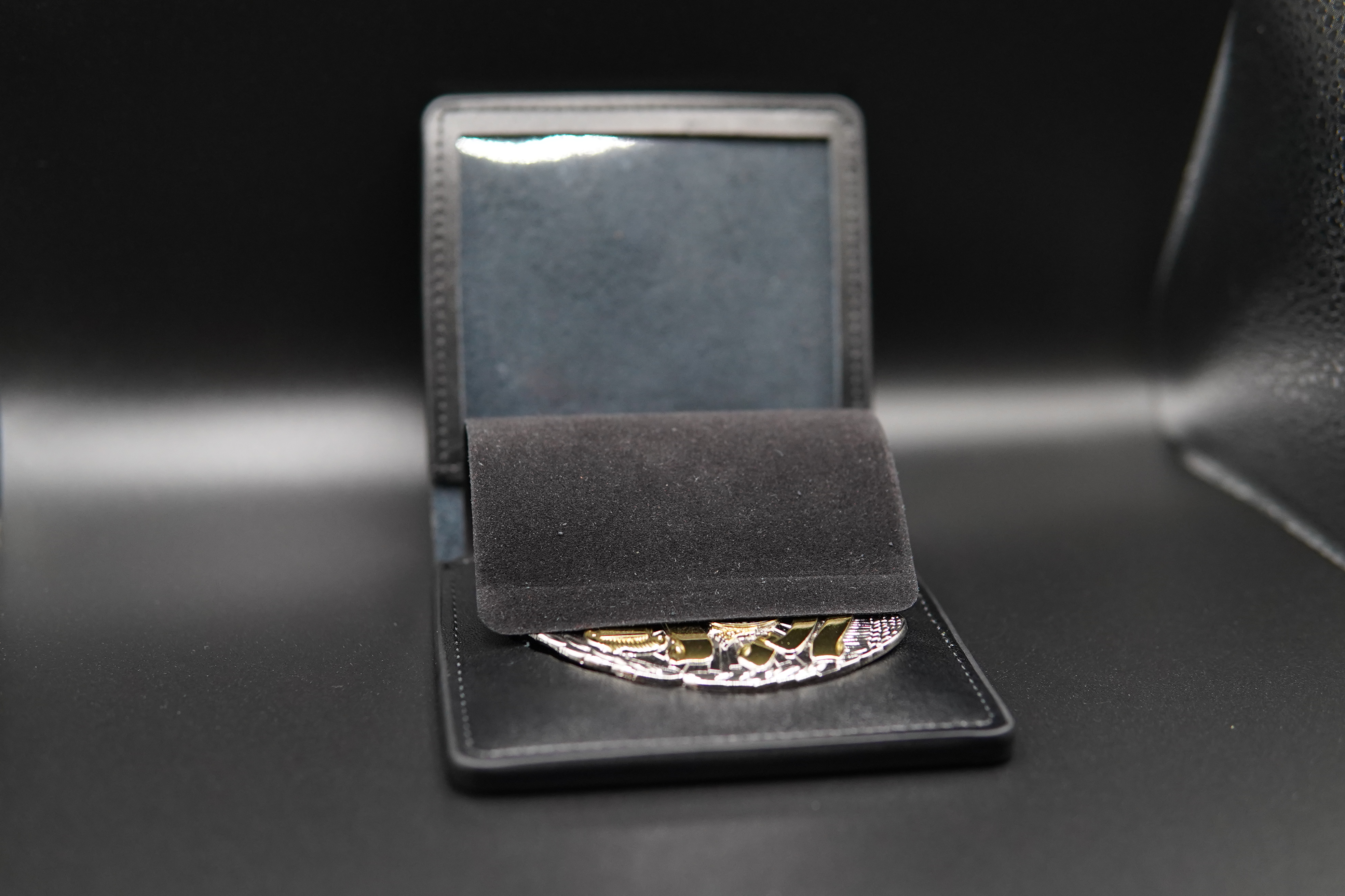 Leather badge wallet with protective flap covering an engraved badge