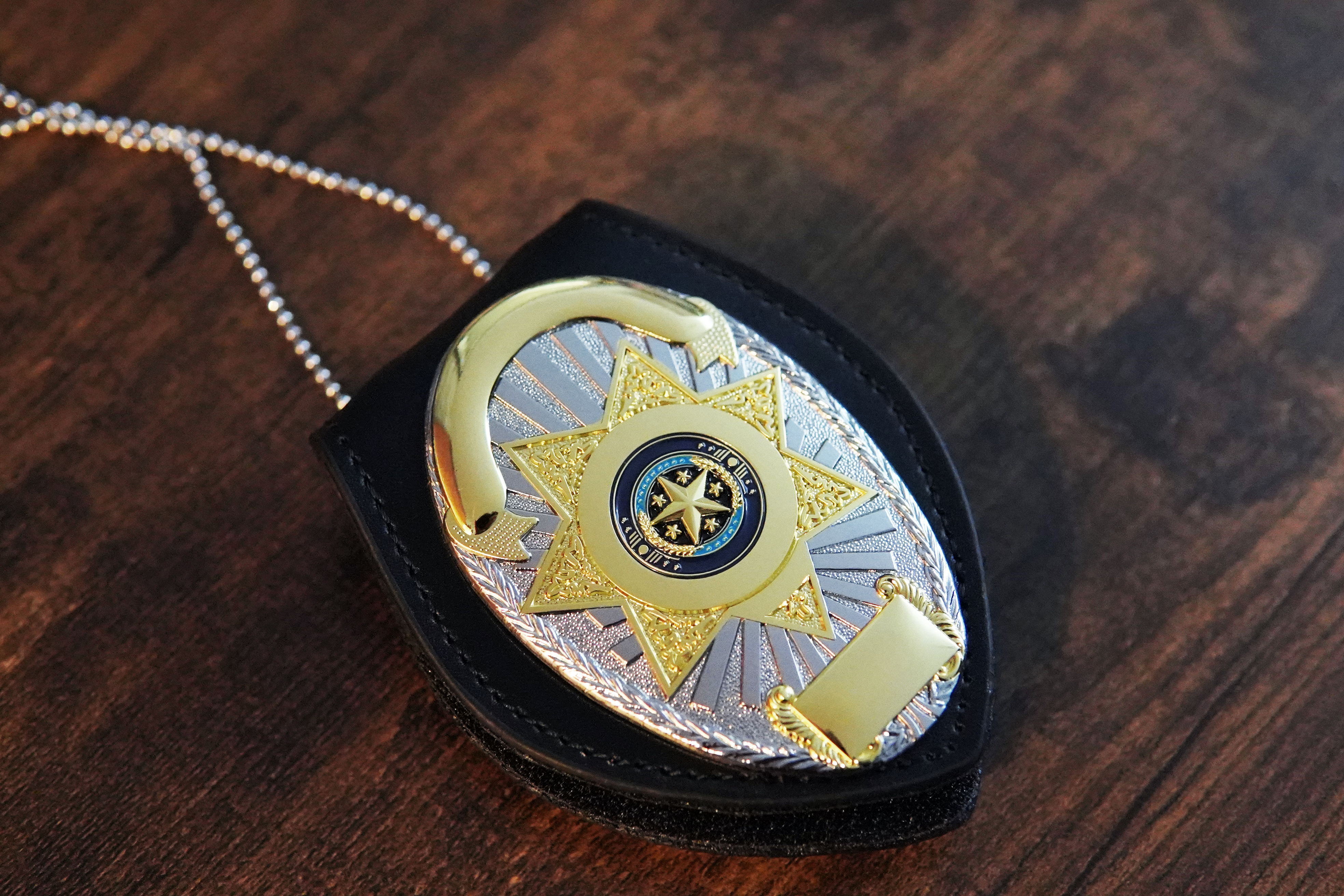Gold and silver engraved police star badge on a leather holder with chain